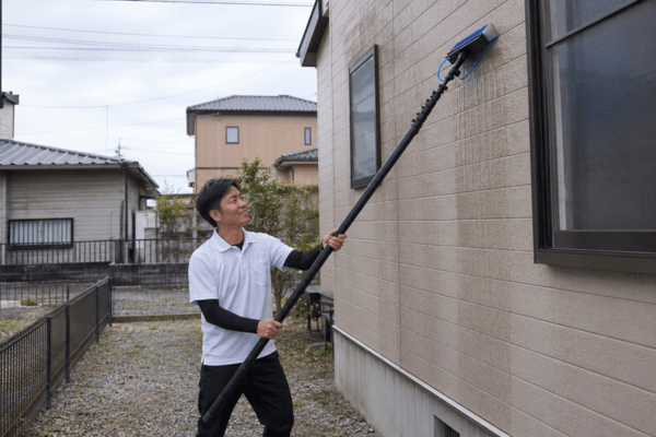キョーサイ洗浄王武雄店が足場を使わず伸縮ポールで住宅外壁を洗浄している写真